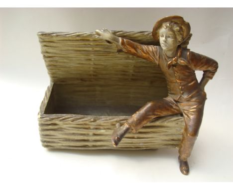 An early 20th Century Continental gilt and painted moulded plaster ornament of rustic boy reclining on the edge of an open wi