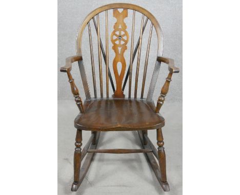 A vintage Windsor wheel back rocking chair with elm seat. H.90cm 
