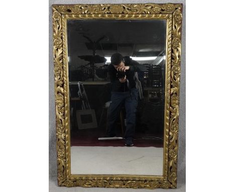 An early 20th century wall mirror in carved and pierced giltwood floral decorated frame. H.122 W.83 