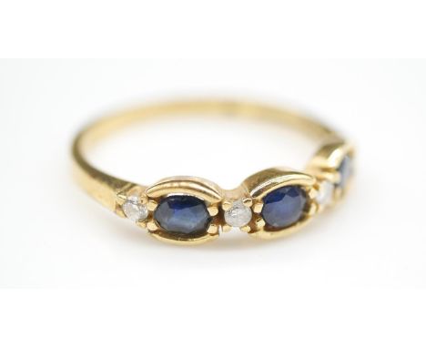 A three stone sapphire, diamond and 18 carat yellow gold ring. Set with three oval mixed cut sapphires with a combined approx