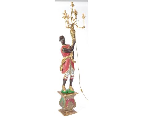 A parcel gilt and silvered floorstanding large figure of a Blackamoor holding a cornucopia shell aloft that has seven branche