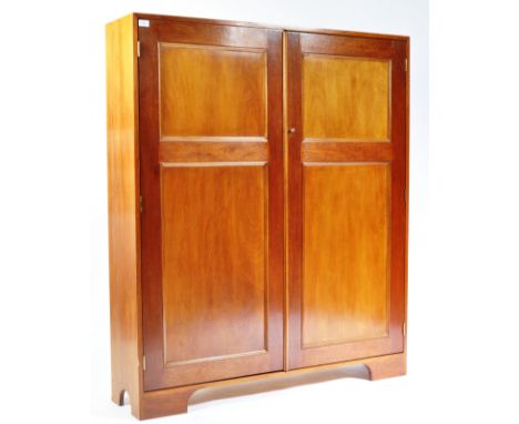 A late 20th century mahogany school cupboard with recessed panel doors and a shelved interior raised on bracket feet formed f