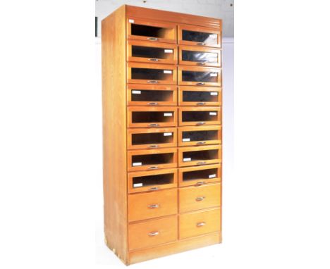 A mid century light oak shop display haberdashery retailers shirt cabinet, fitted with sixteen glaze pull out drawers over a 