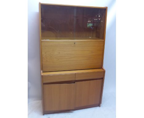 A vintage 20th Century teak bureau having two sliding glass doors above a pull down desk unit and storage beneath