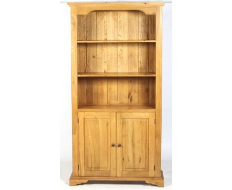 A contemporary solid oak free standing bookcase cupboard. With two adjustable shelves above paneled two door cupboard opening