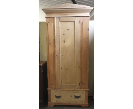A vintage pine wardrobe. With a triangular pediment, the single panelled door opening to reveal five wooden hooks (key presen