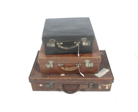 Three vintage leather luggage suitcases. All with a single handle to the top, some with stickers to the exterior, largest L71
