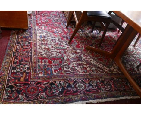 An antique Heriz carpet with central geometric medallion, on a red and cream ground, contained by geometric motifs and border