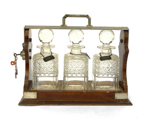 An oak tantalus with three cut glass decanters, with key