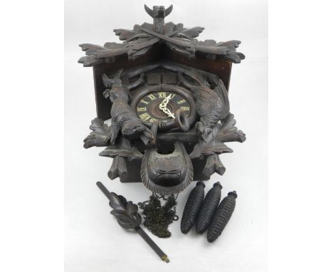 An early 20th century Swiss carved beechwood cuckoo clock, the architectural case mounted with muskets and game, having a Rom