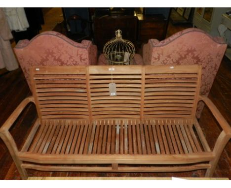 A Contemporary three seater teak garden bench, raised on squared legs.