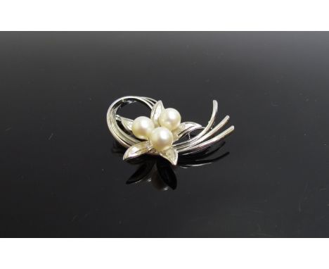 A sterling silver floral form brooch set with three pearls