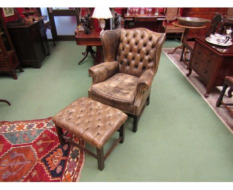 A leather wingback armchair with button back and matching stool