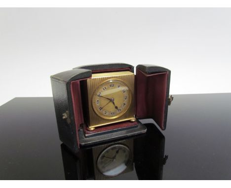 A Deco miniature brass alarm clock with Arabic numerals, Swiss made in travel case, 5.5cm x 5cm