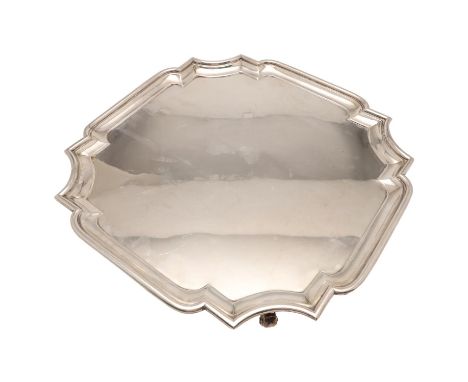 of shaped square outline, with a moulded border, incurved corners and resting on four scroll feet, by Charles Stuart Harris, 