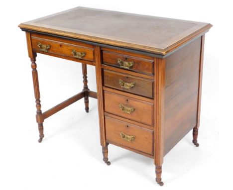 An Edwardian walnut console desk, with brown leather inset top above single drawer with four drawer bank on castors. 