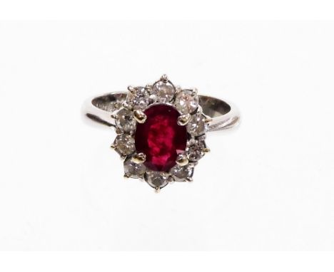 A ruby and diamond dress ring, with oval cut central ruby, 7.8mm x 6mm x 2.4mm, in a four claw setting surrounded by round br