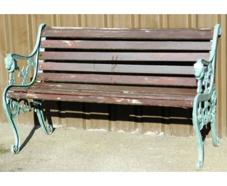 A cast iron and wooden slatted bench, the lion scroll supports painted green on wooden slats, 80cm high, 130cm wide, 46cm dee