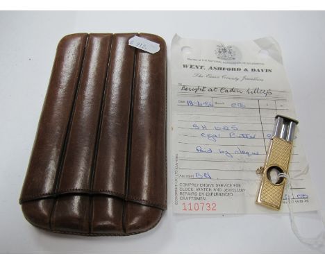 A 9ct Gold Cigar Cutter, allover engine turned, with suspension loop; together with a leather cigar case. (2) 
