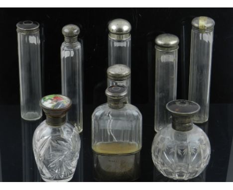 A collection of six silver  topped glass bottles, three having tortoiseshell lids, together with two white metal topped glass