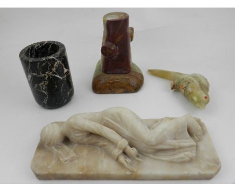 An alabaster paperweight in the form of a reclining woman, together with an onyx parrot perched on a tree trunk, and a marble