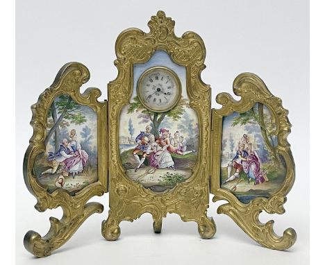 Belle Époque-Tischuhr. Feuervergoldete Bronze in Rocaillenform. Dreiteiliger "Stellschirm" mit Email-Plaketten, diese mit "Wa