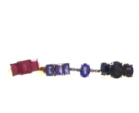 FOUR GEM SET DRESS RINGS, IN NINE CARAT GOLD  comprising a red three stone ring, blue three stone ring, lilac three stone rin