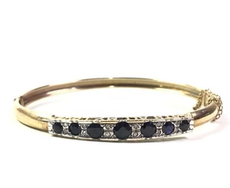 SAPPHIRE AND DIAMOND BANGLE, NINE CARAT GOLD  set with seven round sapphires spaced with small diamondsQty: 9.2g