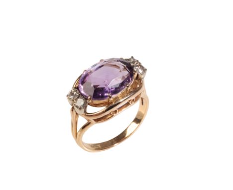 AN AMETHYST AND DIAMOND RING, the oval-cut amethyst, flanked to either side with two round-cut diamonds, on a reeded gold sha