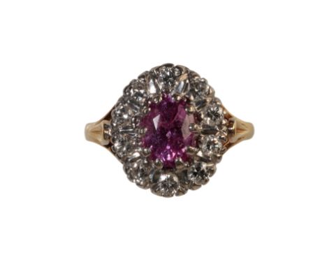 A PINK SAPPHIRE AND DIAMOND RING, the oval-cut sapphire, within a border of ten brilliant-cut diamonds, on an 18ct yellow gol