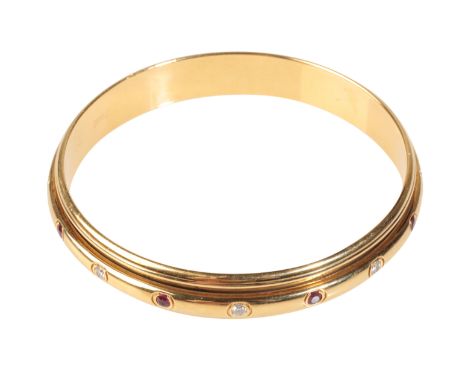 PIAGET; A YELLOW GOLD DIAMOND AND RUBY POSESSION BANGLE, the center rotating section, set with brilliant-cut diamonds and rub