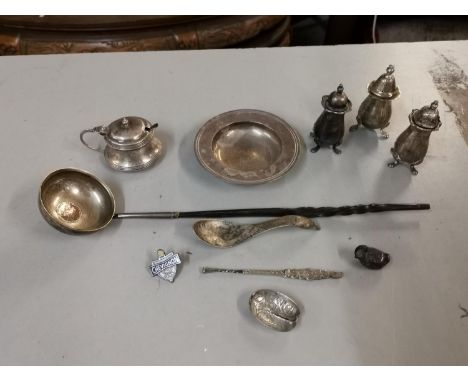 Silver to include a dish, mustard pot, three cruets, spoon, small ladle, 307g. A silver pin cushion in the form of a bird, a 