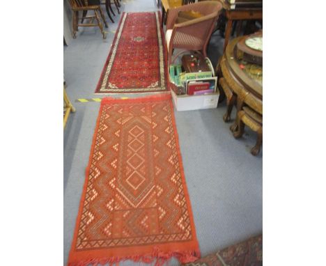 Two rugs comprising a red ground runner and a smaller terracotta ground scatter rug 290cm x 76cm and 147cm x 69cm respectivel