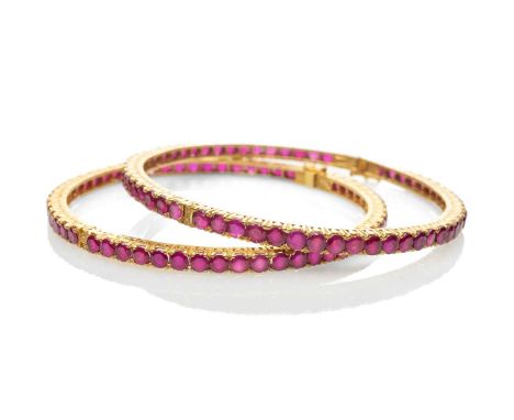 TWO SIMILAR YELLOW METAL BELIEVED RUBY SET HINGED BANGLES, one stamped '22K' the other stamped '22KDM', 54.1gms gross (2)Prov