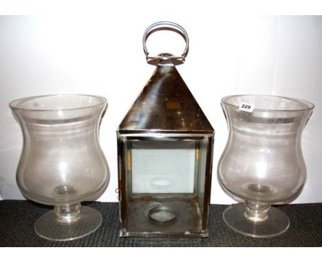 A pair of large glass storm lanterns and a further enclosed candle lamp, storm lantern H. 38cm, other lamp H. 57cm.