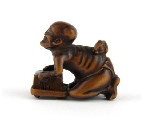 A Japanese Edo period carved fruitwood netsuke of a skeletal figure with one ivory eye and ivory signature panel, H. 3cm. Pos