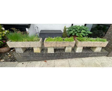 A GROUP OF THREE STONE PLANTERS each comprising a trough, on two stands, planted with a variety of herbs, 40cm high (on stand