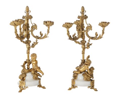 A PAIR OF 19TH FRENCH ORMOLU AND WHITE MARBLE THREE BRANCH CANDELABRA with leaf capped circular sconces, goats head and scrol