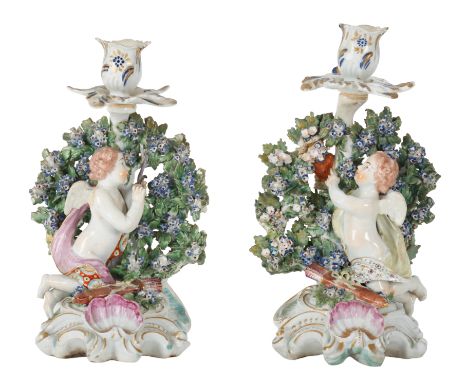 A PAIR OF DERBY PORCELAIN CANDLESTICKS MODELLED AS CUPIDS circa 1770, one of the cupids is holding his bow and arrow, the oth