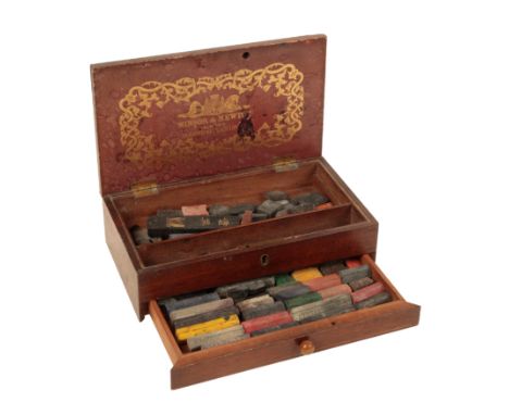 A 19TH CENTURY WINSOR &amp; NEWTON MAHOGANY ARTIST'S BOX containing a variety of paint cakes, the box 6cm high x 23cm wide x 