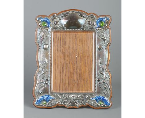 An Art Nouveau silver mounted easel photograph frame. Decorated in relief with flowers and having enamel detailing. Assayed B