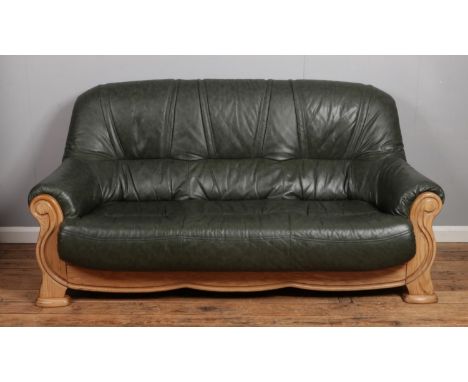 A green leather sofa and matching arm chair. With wooden frame and faux bergere sides.