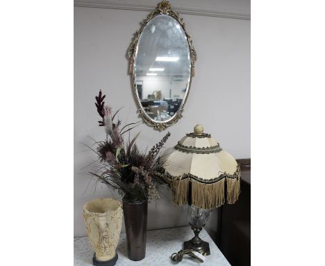 An oval gilt framed bevelled edge wall mirror together with a metal and glass table lamp with shade, contemporary vase of art