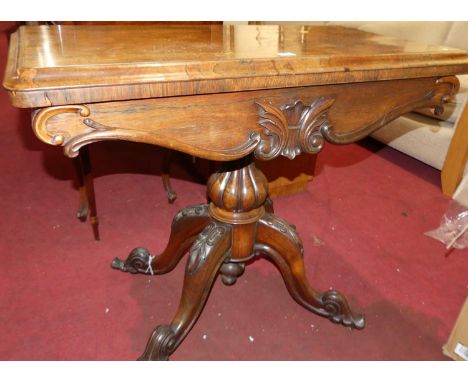 A mid-Victorian rosewood round cornered fold-over baize lined card table, having a swivel top and raised on floral carved hip