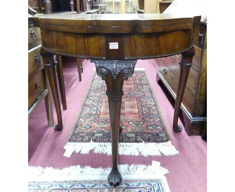 A 1930s figured walnut and cross banded shaped demi-lune baize lined fold-over card table, having a rear pull-out central sup