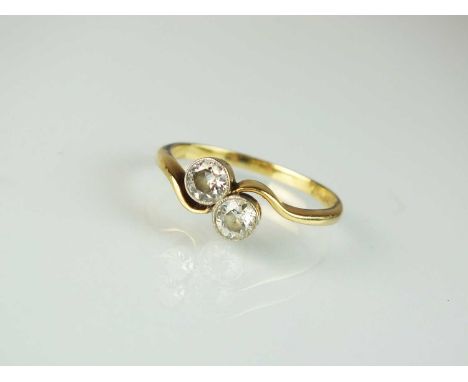 A two stone diamond crossover ring, the transition cut diamonds collet set in white metal to yellow metal shank, stamped '18c