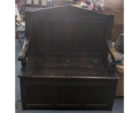 An 18th century oak bench with carved topped rail and panned back with hinge topped seat 136cm h x 129cm w x 56.5cm d Locatio