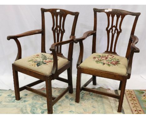 A pair of early 19th century mahogany elbow chairs, in the Chippendale style, with carved backrest and upholstered pad seats.