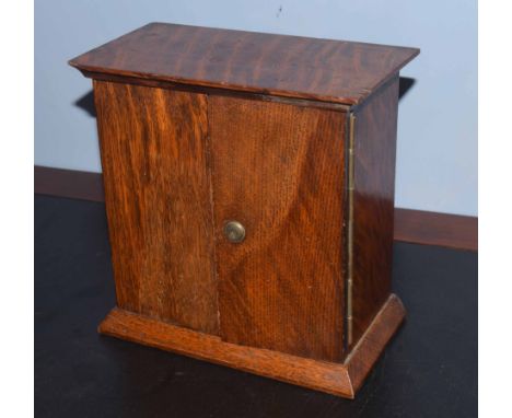 Early 20th century oak key cabinet, of rectangular form with moulded edge over two doors enclosing fitted rows of hooks etc b