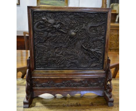 Chinese stained wood table screen, rectangular panel, carved in relief with dragons chasing a flaming pearl, width 45cm.